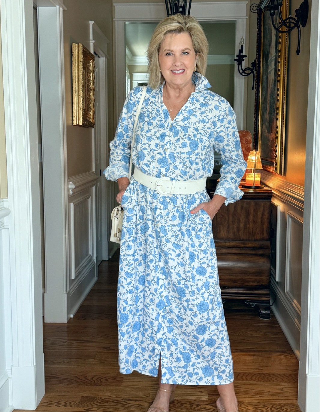 Tania wearing a blue and white floral linen-blend maxi dress with a wide white belt and neutral handbag
